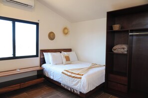 Un dormitorio con cama, banca, armario y ventana.