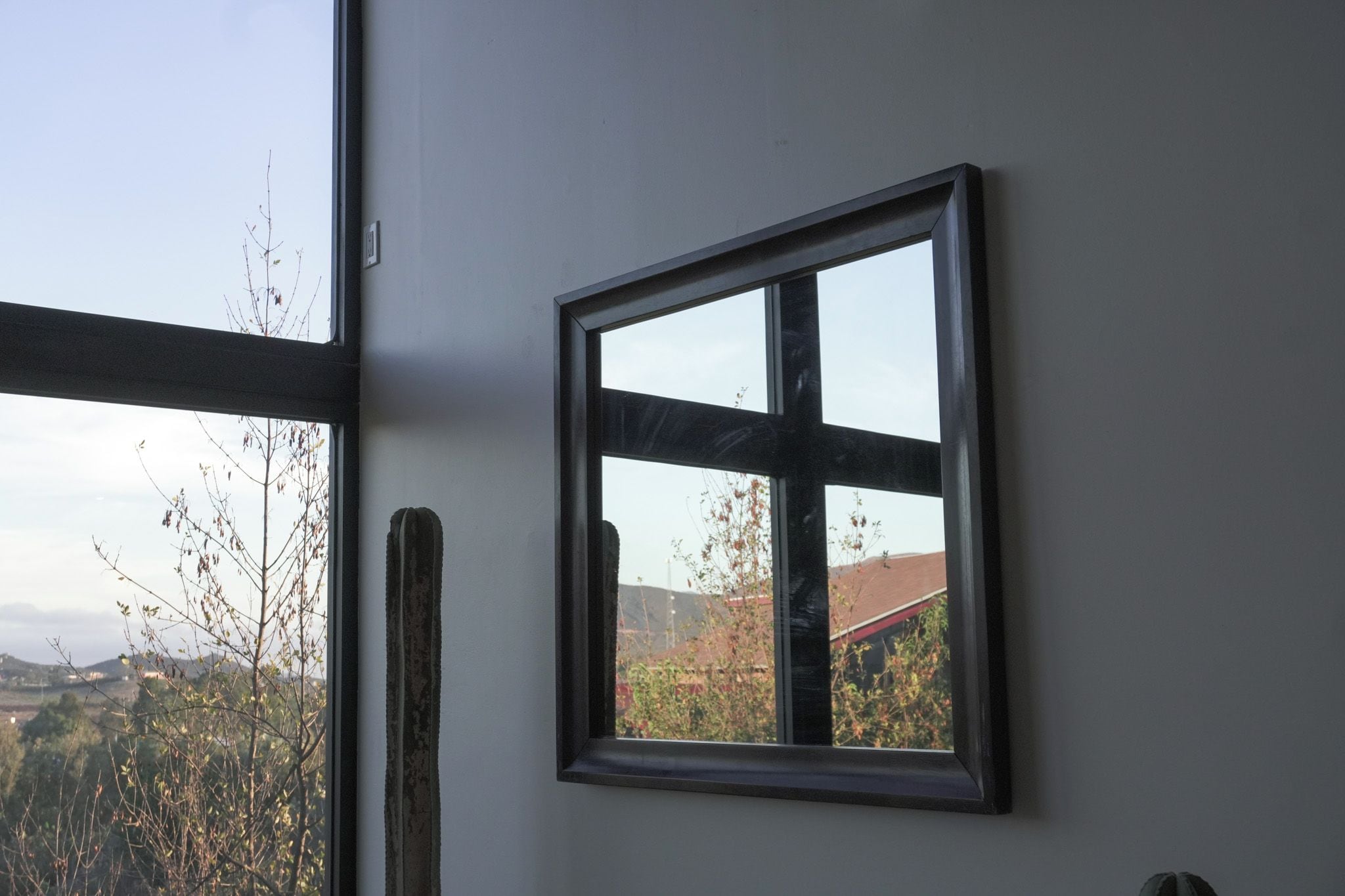 A window with a view of a landscape, a door frame, and a wall.