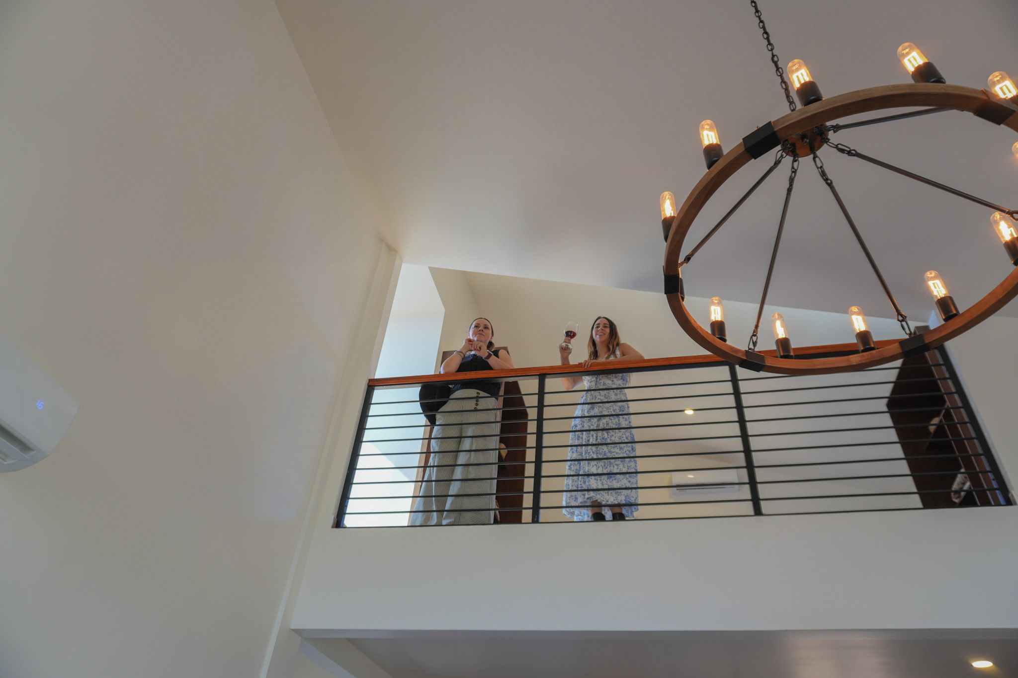 A high ceiling with a circular chandelier and a balcony railing.
