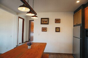 Una cocina con armarios de madera, un refrigerador de acero inoxidable y una mesa de comedor de madera con un florero de flores.