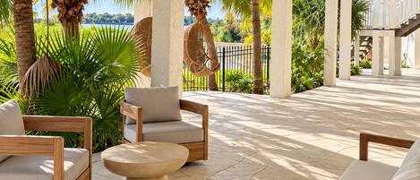 An outdoor patio with wooden furniture and a view of the ocean.
