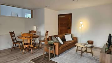 A living room with a wooden dining table, chairs, a sofa, a coffee table, and a floor lamp.