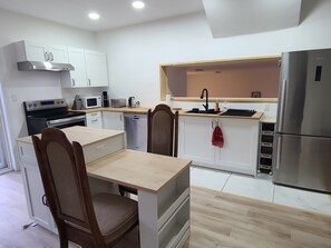 Una cocina moderna con armarios blancos, un refrigerador de acero inoxidable, horno empotrado y microondas.