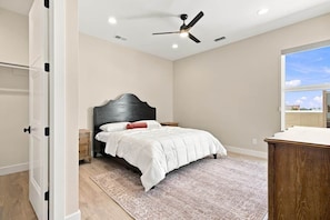 Ein Schlafzimmer mit einem Bett, einem Nachttisch und einem Deckenventilator.