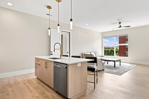 Una cocina moderna con lavavajillas, un comedor con mesa y sillas, y un amplio ventanal con vistas.