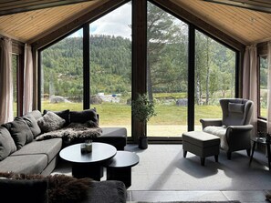 A modern interior with a large window, a sofa, a chair, and a small table.