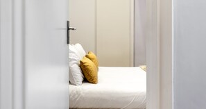 A bedroom with a bed, white bedding, and two pillows. - South Kensington Base Near Hyde Park (London)