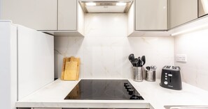 Eine moderne Küche mit einer schwarzen Induktionskochplatte, Edelstahl-Kochgeschirr und einem Toaster.