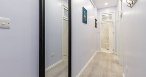 A hallway with light-colored walls, a wooden floor, and a door leading to a bathroom with a marble backsplash. - South Kensington Base Near Hyde Park (London)