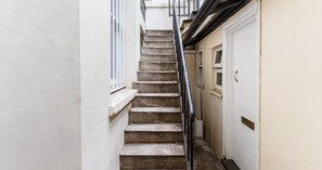 A narrow stairway with a metal handrail leading to a door with a small window. - South Kensington Base Near Hyde Park (London)