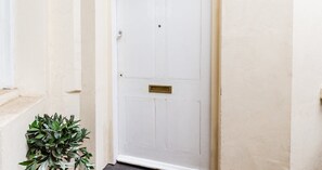 A white door with a brass mail slot and a small plant beside it. - South Kensington Base Near Hyde Park (London)