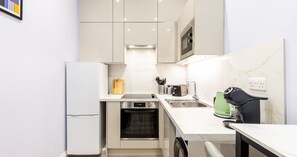 A modern kitchen with a built-in oven, a sink, and a coffee machine. - South Kensington Base Near Hyde Park (London)