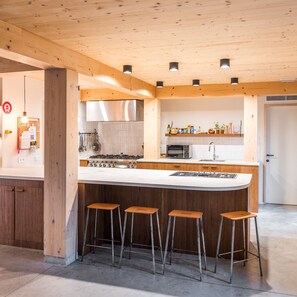 Een moderne keuken met een groot eiland, barkrukken en een roestvrijstalen afzuigkap.