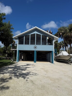 A two-story building with a garage and a covered boat. - 3-bedroom stilt home designed for hunters, fisherman, scallopers & nature lovers (Crystal River)