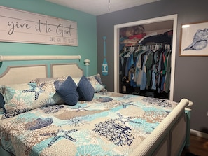 A bedroom with a bed, a closet, and a wall sign.