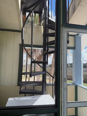 A spiral staircase with a metal railing, leading to an upper level. - 3-bedroom stilt home designed for hunters, fisherman, scallopers & nature lovers (Crystal River)