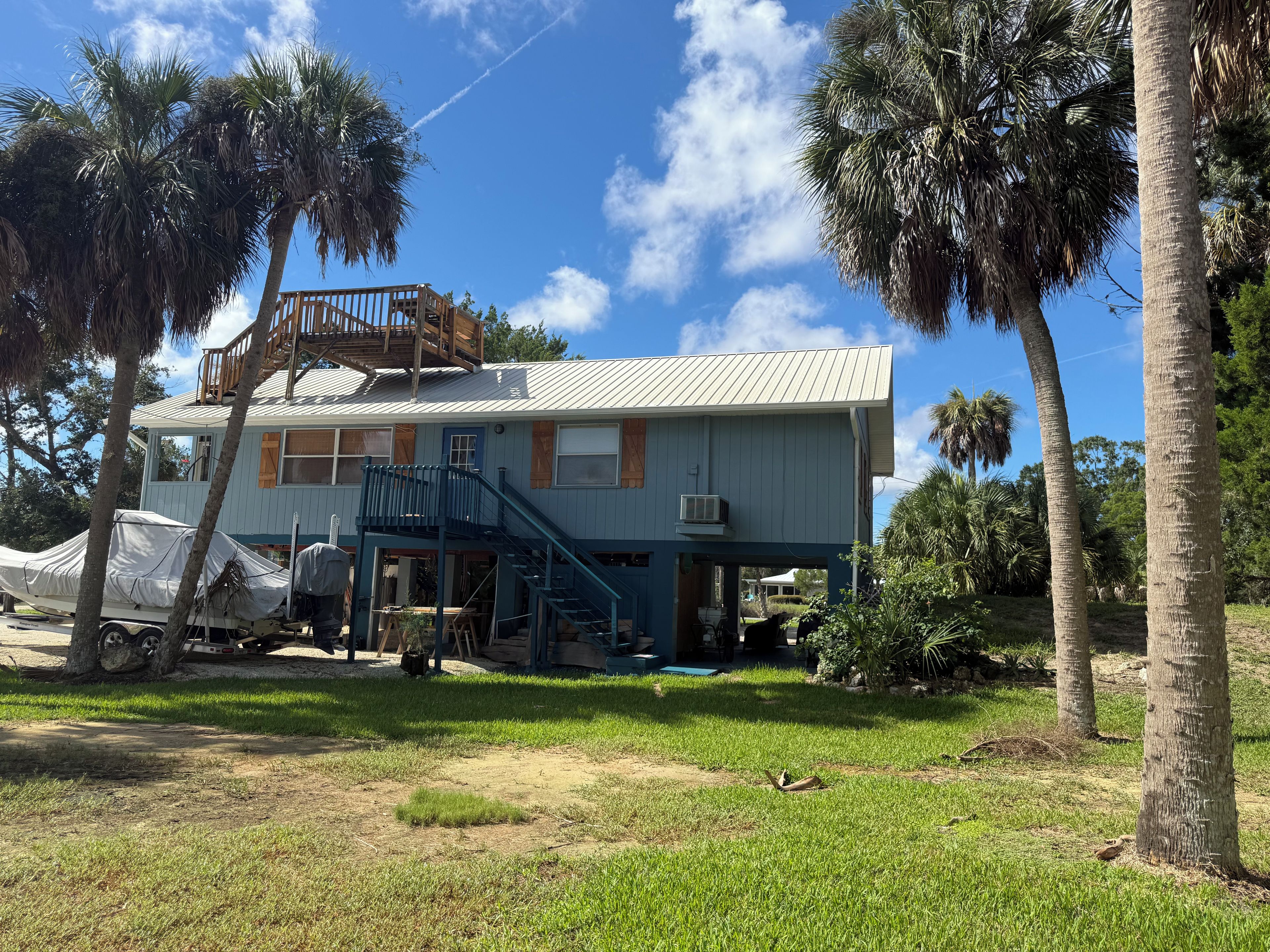 A two-story house with a balcony, a covered vehicle, and a lawn.