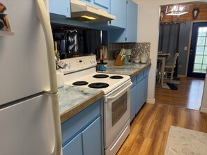 A kitchen with a white stove, blue cabinets, and a wooden countertop. - 3-bedroom stilt home designed for hunters, fisherman, scallopers & nature lovers (Crystal River)