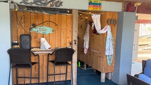 A rustic wooden interior with a bar area, two wicker chairs, and a blue floor.
