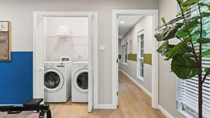 A laundry room with two front-loading washing machines, a drying rack, and a bench. - The Reset Estate by Avantstay Book for ACL Sleeps 22 Pool + Hot Tub + Sauna Casita 2 Acres (Austin)