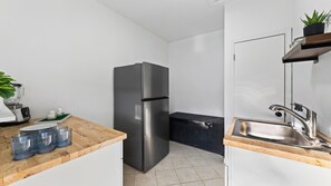 A compact kitchen with a stainless steel refrigerator, a wooden countertop, a sink, and a small potted plant. - The Reset Estate by Avantstay Book for ACL Sleeps 22 Pool + Hot Tub + Sauna Casita 2 Acres (Austin)