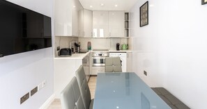 Een moderne keuken met een eethoek, inbouwapparatuur en een flatscreen televisie.