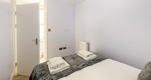 A bedroom with a bed, a radiator, and a door. - South Kensington Base Near Chelsea (London)