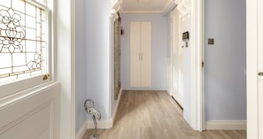 A hallway with a wooden floor, white walls, and a door with a number plate. - South Kensington Base Near Chelsea (London)