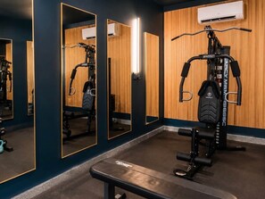 A gym with exercise equipment, mirrors, and a bench. - The Cove & Beach Nook | Sleeps 16 | Spa · Theater (Walton County)