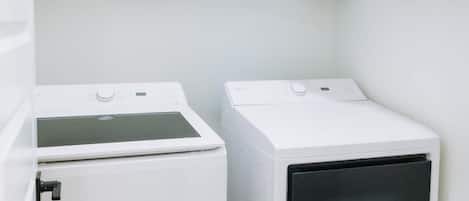 Une buanderie avec deux machines à laver blanches et des placards.
