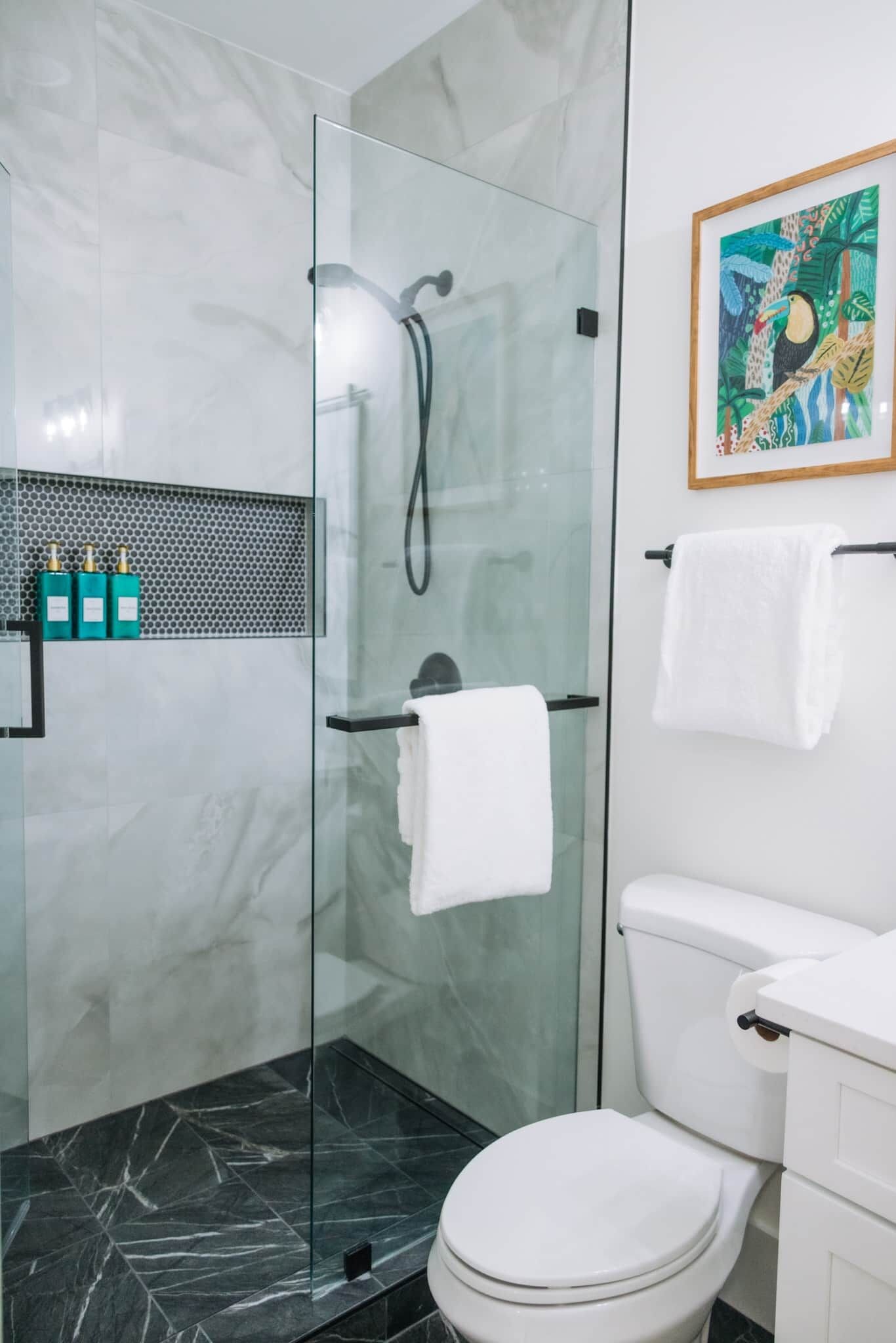 A modern bathroom with a glass-enclosed shower, a toilet, and a sink.