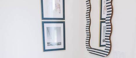 A room with a wooden dresser, two framed pictures, and a large mirror on the wall.