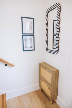 A room with a wooden dresser, two framed pictures, and a large mirror on the wall.