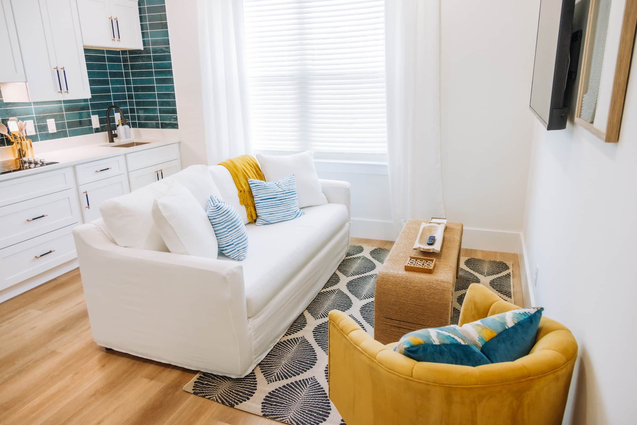 A modern living room with a white sofa, a yellow armchair, and a coffee table.