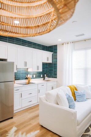 A modern kitchen with white cabinets, a stainless steel refrigerator, and a green tiled backsplash.