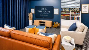 Een speelkamer met een televisie, boekenkasten, een bank en een divan.