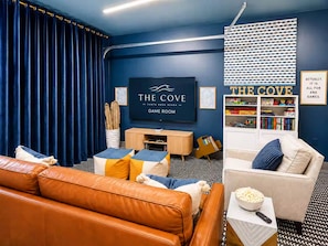 Een speelkamer met een televisie, boekenkasten, een bank en een divan.