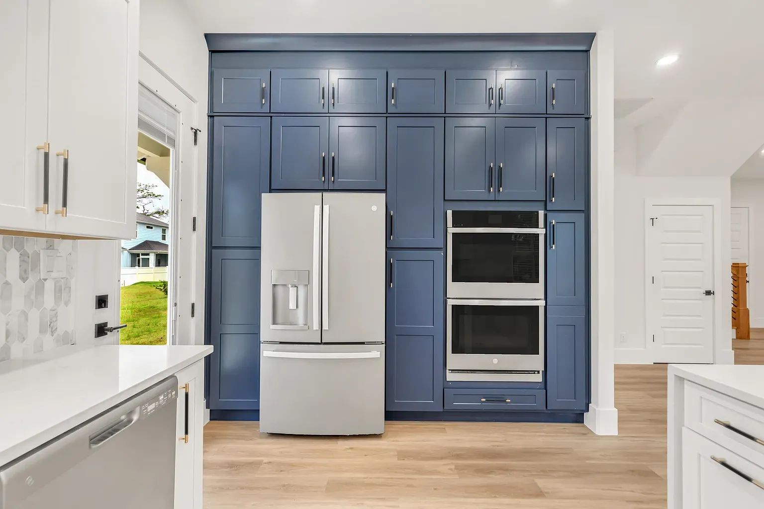 A modern kitchen with a built-in refrigerator, double oven, and blue cabinetry.