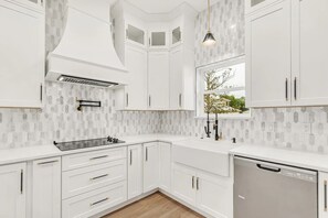 Une cuisine moderne avec des meubles blancs, un lave-vaisselle en acier inoxydable et une fenêtre donnant sur un paysage verdoyant.