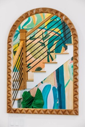 Eine Treppe mit einem hölzernen Geländer und einem farbenfrohen, abstrakten Gemälde an der Wand.