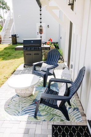 A patio with outdoor furniture, a grill, and a house in the background. - The Cove | 4BR · 12 Guests | Spa · Theater · Gym (Walton County)