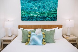 A neatly made bed with a wooden headboard, flanked by two bedside tables with lamps, and a large wall art piece above. - The Surf Shack @ The Cove | 2BR · 6 Guests | Gym · Games (Walton County)