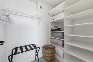 Ein weißer Kleiderschrank mit Regalen und Ablagefläche, ein schwarzer Wäscheständer und ein gewebter Korb.