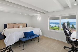 Ein Schlafzimmer mit einem großen Bett, einer Bank, einem Schreibtisch und Seeblick.