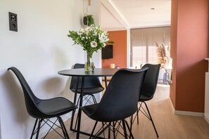 A dining area with a round table and four chairs, a vase with flowers, and a television on the wall. - 't Bunga huiske (Bunga Holidays) (Lanaken)