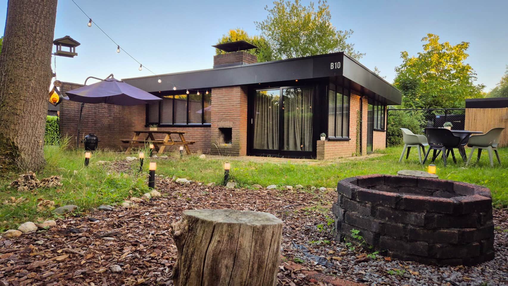 A modern house with a brick exterior, a wooden deck, and a fire pit.