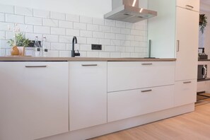 A modern kitchen with white cabinetry, a stainless steel faucet, and a built-in oven. - 't Bunga huiske (Bunga Holidays) (Lanaken)