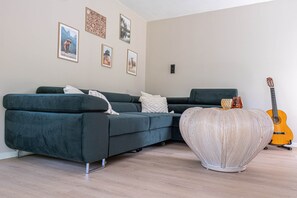 A modern living room with a dark green sofa, a heart-shaped woven stool, and a guitar. - 't Bunga huiske (Bunga Holidays) (Lanaken)