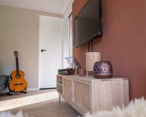 A living room with a wooden cabinet, a guitar, a television, and decorative items. - 't Bunga huiske (Bunga Holidays) (Lanaken)