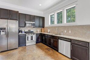 A modern kitchen with dark cabinetry, stainless steel appliances, and a large window providing natural light. - Spacious 4 BDRM I Central Austin I Sleeps 14 (Austin)